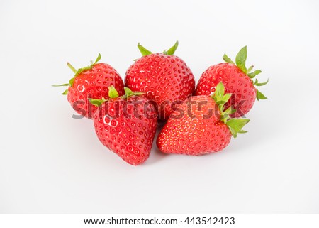 Cluster of ripe red whole fresh strawberries with green stalks and flower buds on a light grey background with.