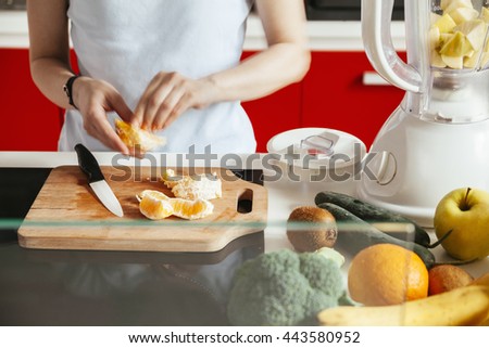 Young Woman In A Kitchen Cutting Fruit For A Smoothie