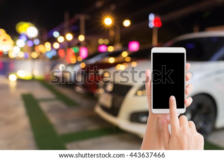 woman use mobile phone and blurred image of car park at night with beautiful bokeh from the lights