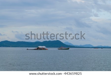 a selective focus picture of boats in sea with a group of tourists and mountain at background