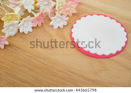 Small pastel flowers on upper left corner of wooden board and white empty sign with bright pink border on the right side. All items ate made of sugar fondant and all are edible - empty space for text