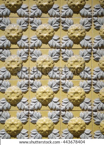 A piece of an old yellow floral ceramic tile in Portugal on the wall of a house