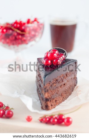 A slice of chocolate pie covered by red current on the white wooden background. Selective focus and small depth of field.