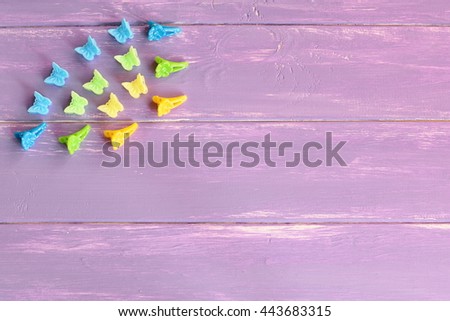 Assortment of plastic hair clips for girls. Blue, yellow, green hair clips on lilac wooden background with empty space for text. Girl bright summer hair accessories Royalty-Free Stock Photo #443683315