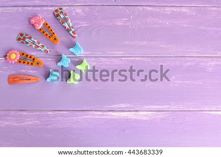 Bright colored hair clips for girls on lilac wooden background with copy space for text. Set of colorful hair clips. Girl fashion background  Royalty-Free Stock Photo #443683339