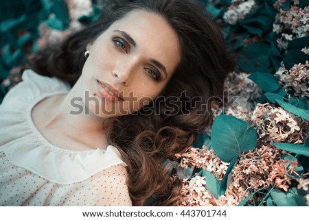 Teen beautiful girl lying on lilac flowers background. Portrait close up