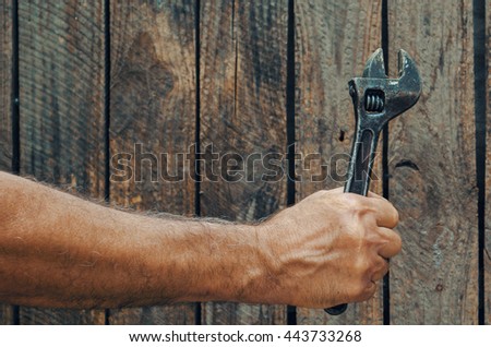 Hand holding vintage adjustable wrench on a wooden background