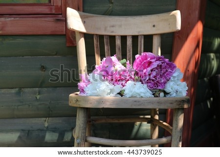 Garden decoration with old wooden chair, bunch, bouquet of white and pink peonies, natural light and shadows, sunny summer day in garden
