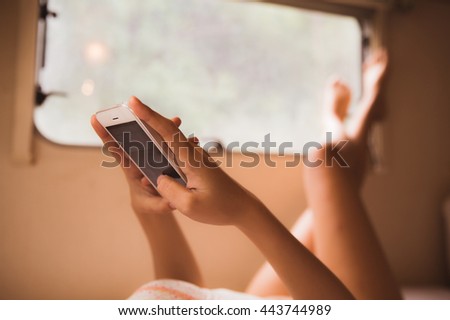 Women are playing phone resting on a bed