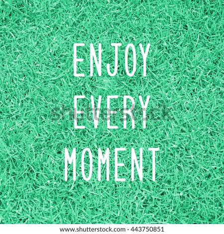 Enjoy every moment. Inspirational quote on grass field.