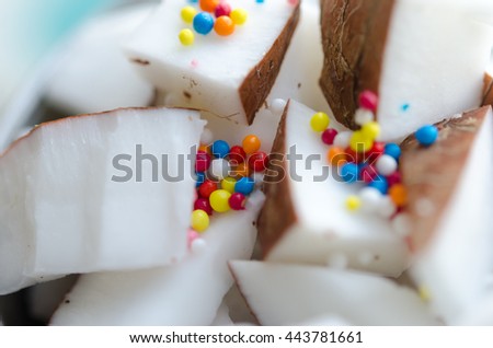 Coconut cubes with color candys in a bowl. Macro photo.