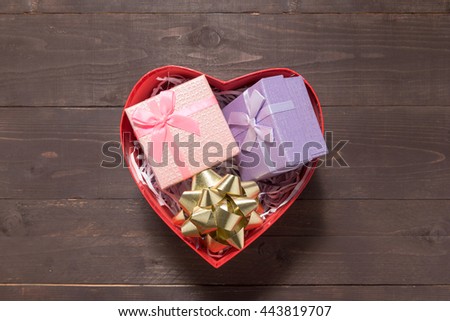 Gift boxes are in heart box, on the wooden background with empty space.