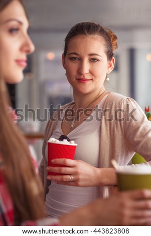 Toned picture of pretty lady drinking delicious coffee while sitting in cafe or restaurant. Woman looking at camera and spending free time with friends.