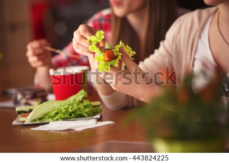 Closeup toned picture of lady eating vegetarian dishes in cafe or restaurant while sitting at wooden table. Vegetarian concept.