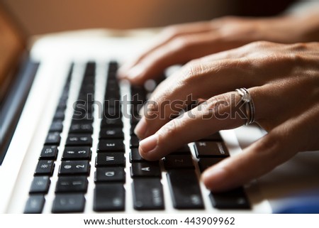 Delicate secretary hands type on a laptop keyboard.