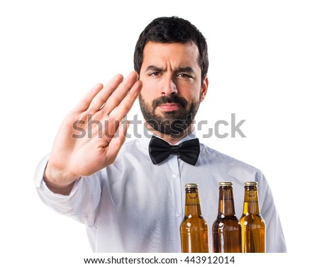 Waiter with beer bottles on the tray making stop sign