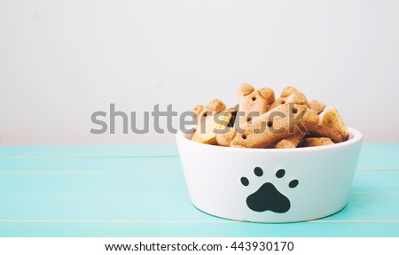 Dog treats in a bowl on wooden table Royalty-Free Stock Photo #443930170
