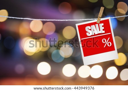 Sale paper label in photo frame paper hanging on bright spot blurred background, discount banner.