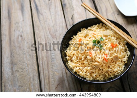 Instant noodles, fried pork, and vegetables on wooden background