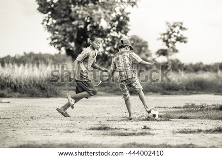 The boys are playing football in the sunshine day. Black and white picture style.
