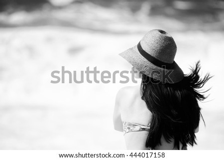 Long haired brunette woman with brown straw hat at beach - in black and white