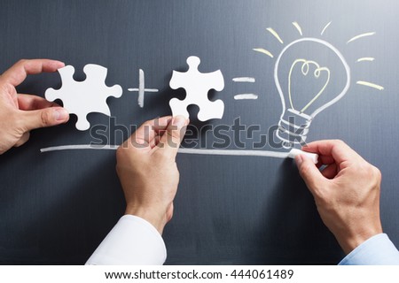 Solving puzzle together. Drawing light bulb on blackboard.
Combining the wisdom for developing new idea.
 Royalty-Free Stock Photo #444061489