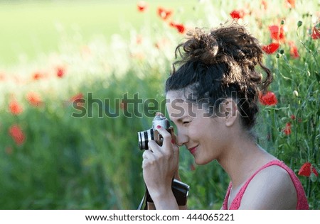 Young woman photographing with a poppy field 