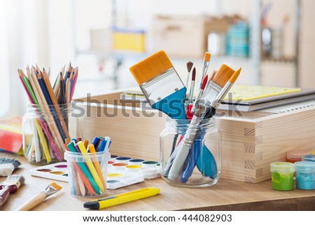 Paint brushes and crafting supplies on the table in a workshop. Royalty-Free Stock Photo #444082903