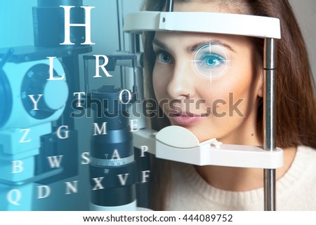 Cute young adult brunette woman at the future clinic checks her vision. Virtual sensors for checking vision. Ophthalmology. Future medicine and health concept. Royalty-Free Stock Photo #444089752