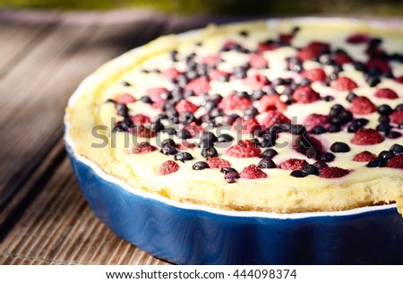 Sunny Photo with a morning breakfast in a rustic style. Cheesecake with raspberries and blueberries on wooden table. Selective focus picture