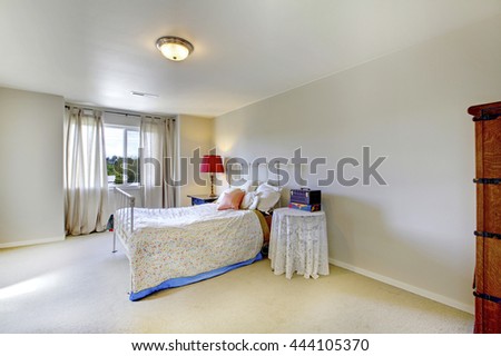 Ivory wall bedroom with white iron bed and red lamp on the nightstand. Also beige carpet floor.