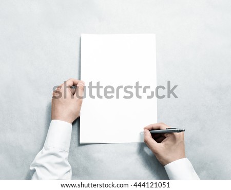 Hand holding blank agreement mockup and signing it. Arm in shirt hold clear document template mock up. Contract surface design. Simple pure legal paper print display. Reading contract statement. Royalty-Free Stock Photo #444121051