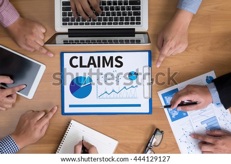 CLAIMS  Business team hands at work with financial reports and a laptop, top view