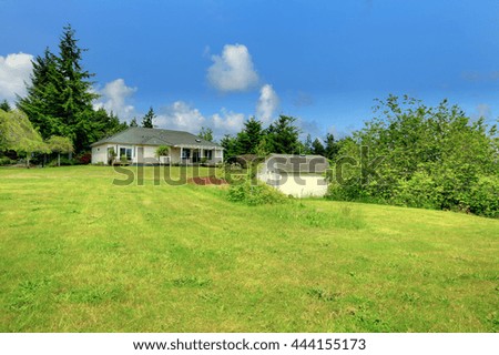 Farm house backyard with a small shed and green lawn with bushes and trees.