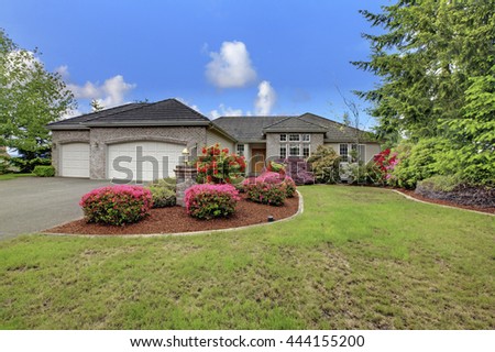Luxury house exterior with brick trim, tile roof and french windows. Front yard landscape with lawn