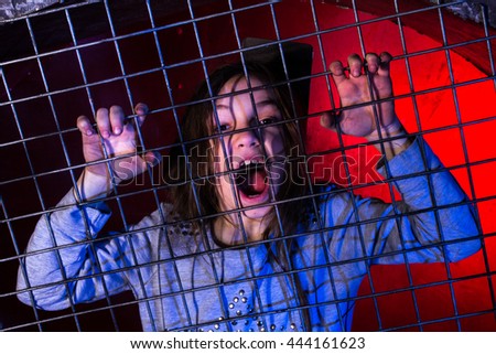 Screaming girl behind grid. Angry girl at fence.
