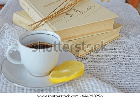 coffee with lemon, white coffee cup, a book in baa black coffee and lemon white cup of coffee and a slice of lemon on a white tablecloth, two cups of coffee