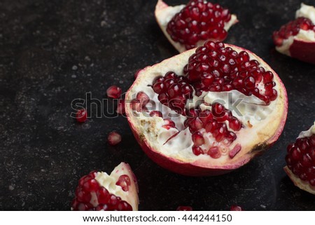 Red juicy pomegranate on dark marble background. Healthy, antioxidant, fresh, gourmet, delicious, organic fruit. Ingredient for grenadine. Close-up and copy space.