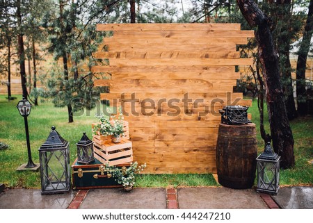 Rustic wedding photo zone. Hand made wedding decorations includes Photo Booth, wooden barrels and boxes, lanterns, suitcases and white flowers and vintage typewriter standing on stump. Horizontal shot