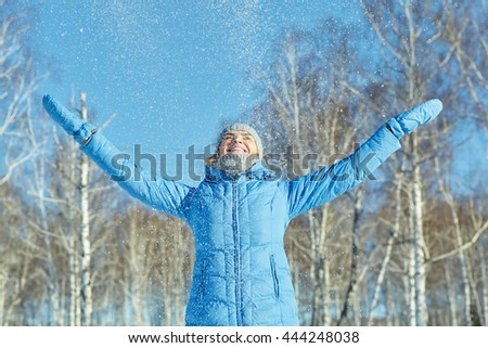 woman on the winter walking in the park falling snow