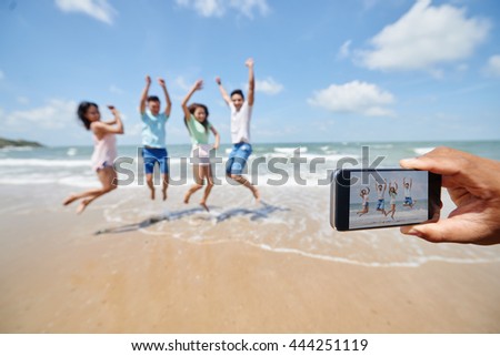 Somebody taking photo of friends jumping at the beach