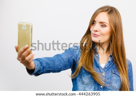 Technology internet and happiness concept. Young fashion woman in denim shirt taking self picture selfie with smartphone camera