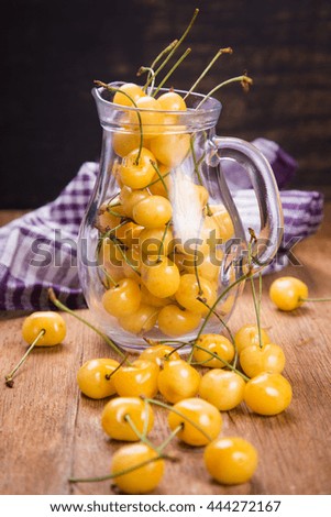 some ripe raw yellow sweet cherry in transparent jug in studio