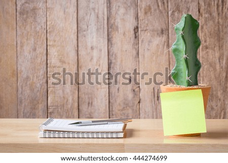 Pencil on a notebook paper with sticker note cactus clay pots on a wooden background. picture used for add text or education message.