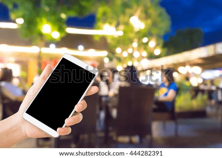 woman use mobile phone and blurred image of people in the restaurant at night,with beautiful bokeh from the lights