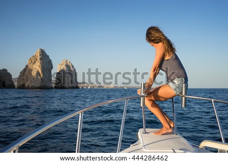 Young woman in the boat at sunset near the rock formations around the Arch in Cabo San Lucas, Mexico.  Royalty-Free Stock Photo #444286462