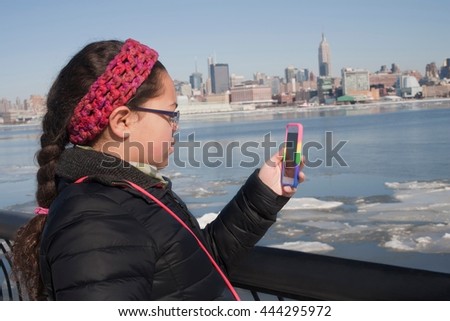 Young girl taking photograph of skyline using smartphone, New York, NY, USA