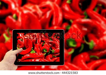 Tablet photography concept. Taking pictures on a tablet. Red chili pepper high contrast background