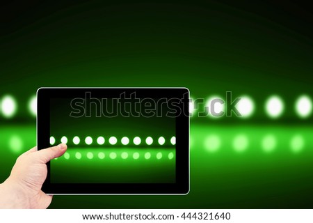 Tablet photography concept. Taking pictures on a tablet. Play of green light on defocusing blur led lamps background
