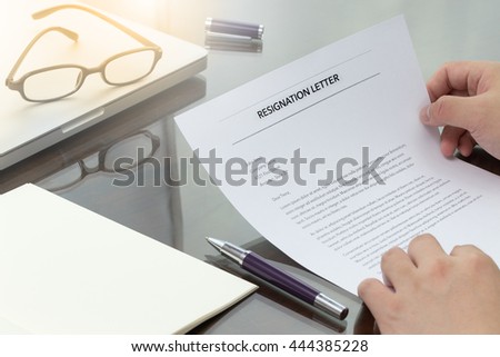 Businessman review his resignation letter on his desk before sending to his boss to quit his job with laptop computer and eye glasses.
